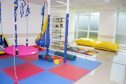 Sala de recreação infantil com brinquedos coloridos e balanços que oferece atendimento médico gratuito.