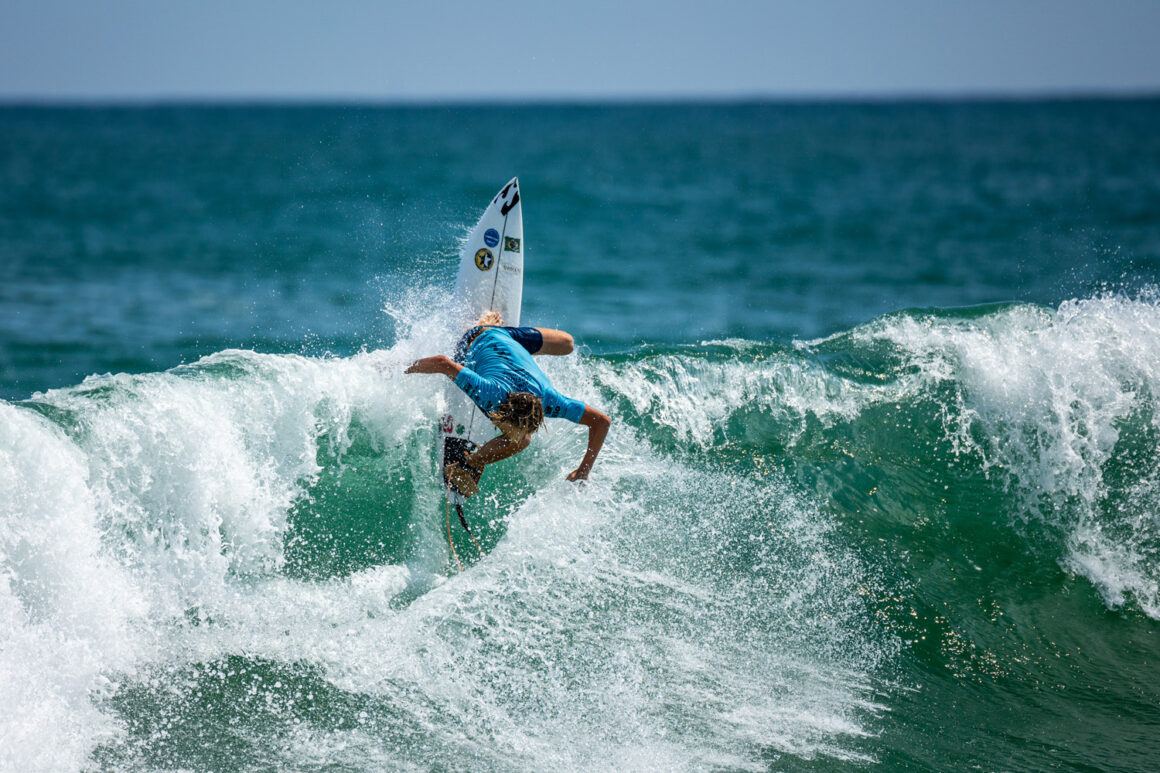 Surfista pegando onda em prancha de surf na Praia da Macumba durante o ISA World Junior Surfing Championship 2023.