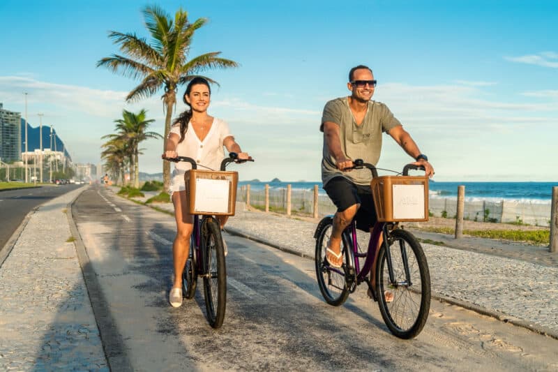 Um casal andando de bicicleta na praia perto do Grand Hyatt Rio de Janeiro.